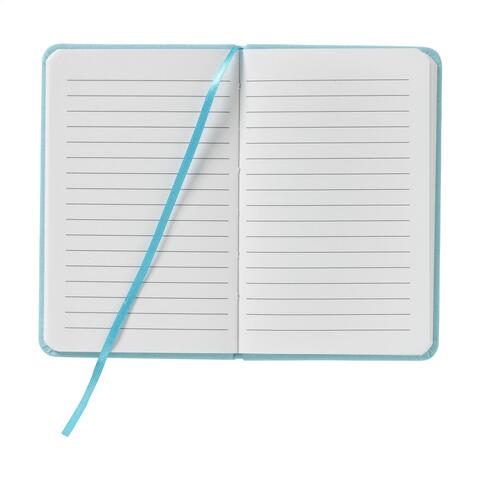 Lyseblå notesbog i A6-format med hårdt cover af bomuld, 80 siders cremefarvet og linjeret papir, elastiklukning, bundet ryg, trykt logo og silkebånd.