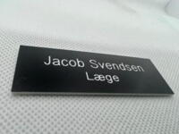 Navneskilt i plast sort/hvid 70x25 mm med graveret navn & titel